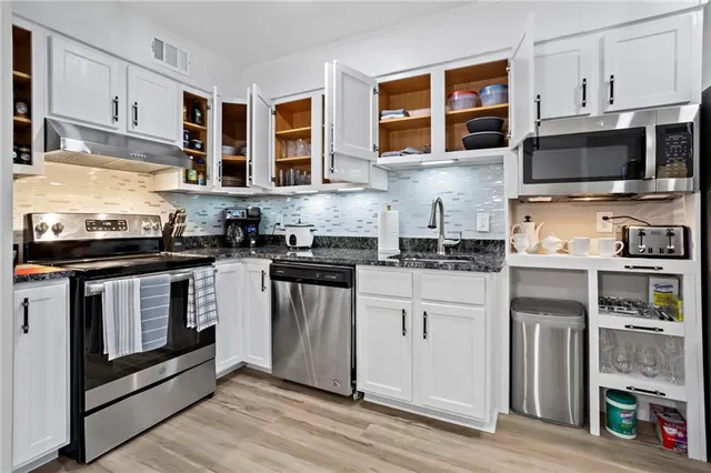 a kitchen with stainless steel appliances granite countertop a stove microwave and cabinets