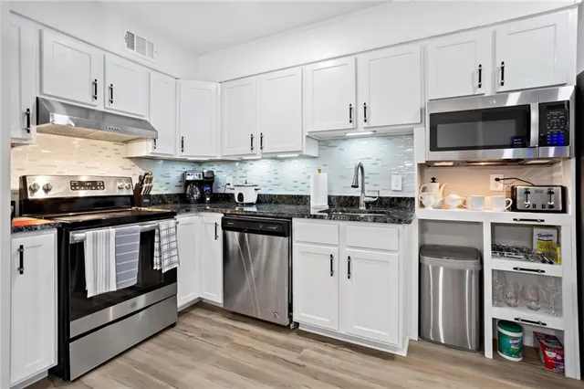 a kitchen with stainless steel appliances granite countertop a stove a microwave and a refrigerator