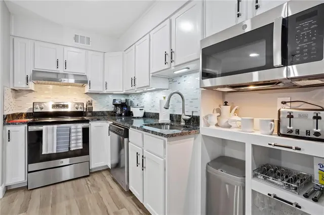 a kitchen with stainless steel appliances granite countertop a sink a stove and cabinets