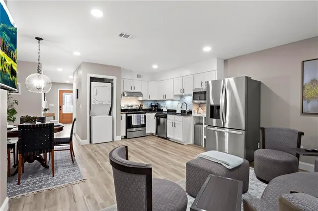 a kitchen with stainless steel appliances granite countertop a refrigerator a stove a sink a dining table and chairs