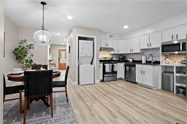 a kitchen with stainless steel appliances kitchen island granite countertop a table chairs and a refrigerator
