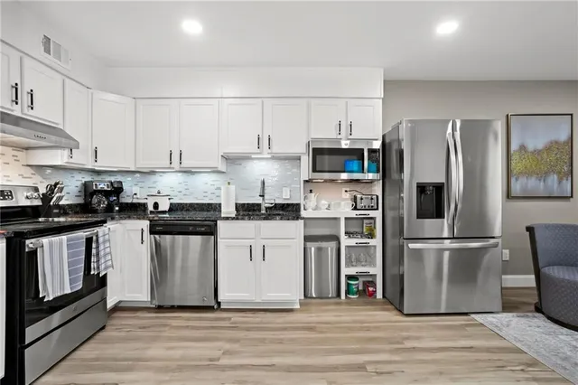 a kitchen with stainless steel appliances a refrigerator stove and white cabinets