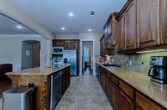 a kitchen with kitchen island granite countertop wooden cabinets a sink and dishwasher