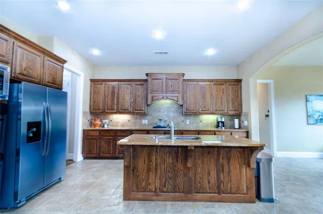 a kitchen with kitchen island granite countertop wooden cabinets and a refrigerator
