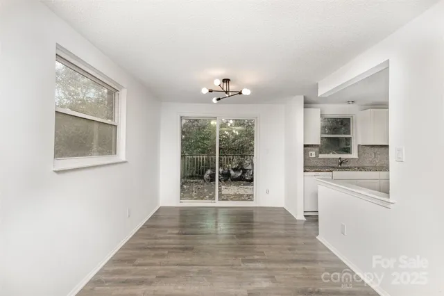 a view of an empty room with a kitchen and a window
