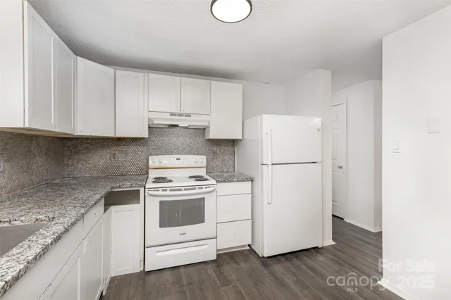 a kitchen with a white cabinets and wooden floor