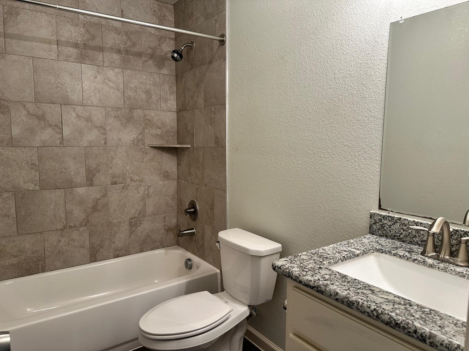 628 Luke Street, Unit A Dayton, TX 77535 - Photo 14 of 26 a bathroom with a granite countertop toilet sink and shower