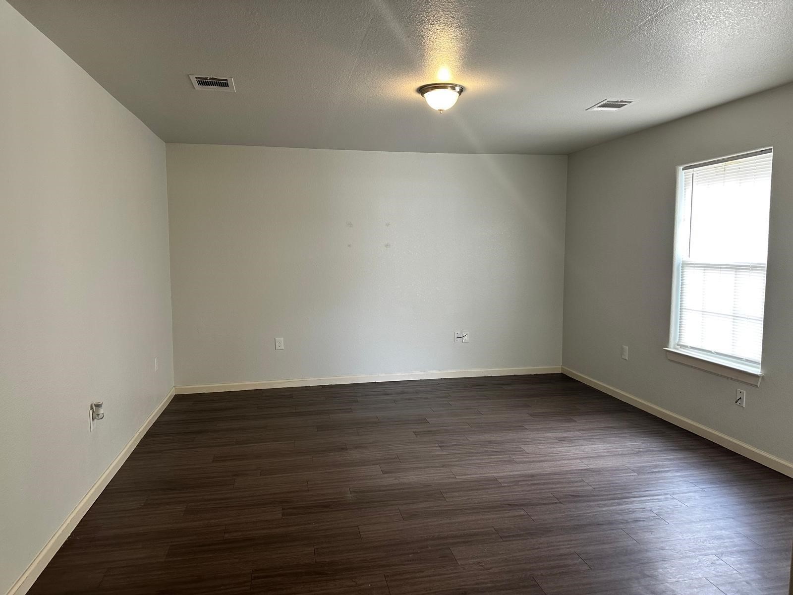 628 Luke Street, Unit A Dayton, TX 77535 - Photo 5 of 26 a view of an empty room with wooden floor and a window