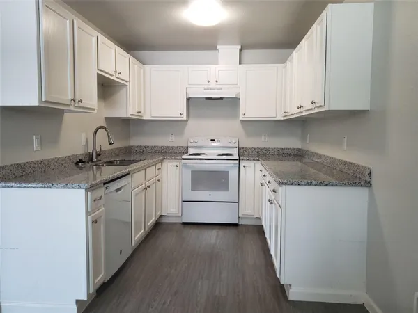 a kitchen with granite countertop white cabinets and white appliances