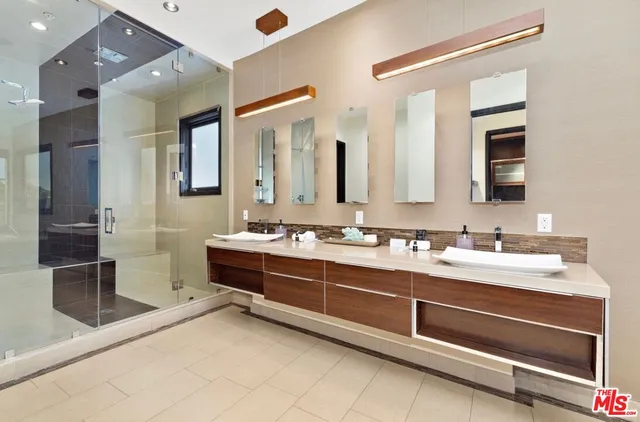 a spacious bathroom with a double vanity sink a mirror and a shower