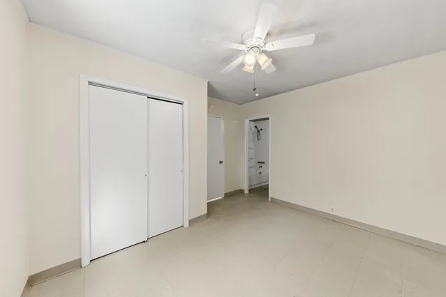 an empty room with a chandelier fan and windows