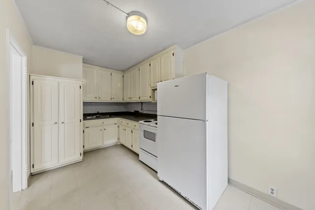 a kitchen with white cabinets and white appliances