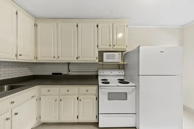 a kitchen with granite countertop white cabinets and white appliances