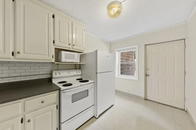 a kitchen with white cabinets and white appliances