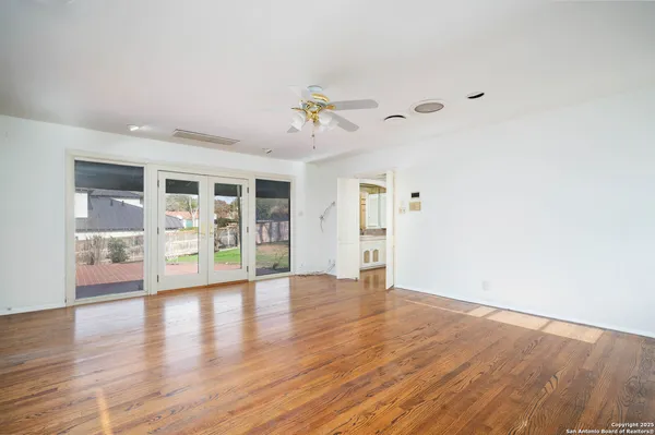 a view of an empty room with a window and wooden floor