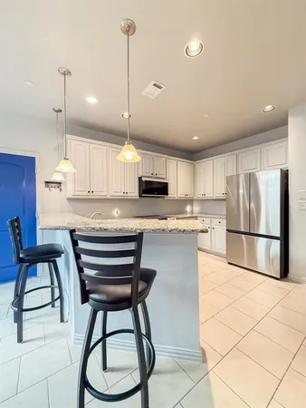 a kitchen with stainless steel appliances granite countertop a stove a refrigerator a oven a sink a dining table and chairs