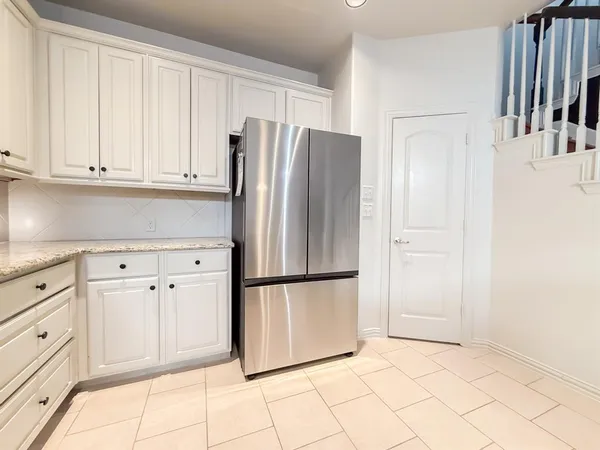 a kitchen with white cabinets and refrigerator