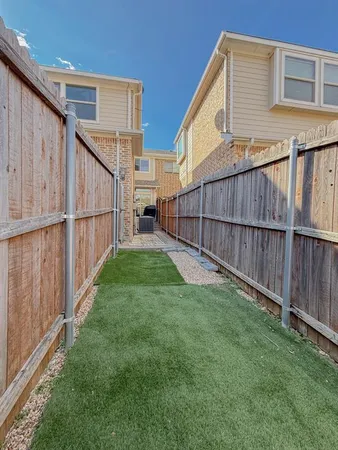 a view of a backyard with wooden fence and large trees