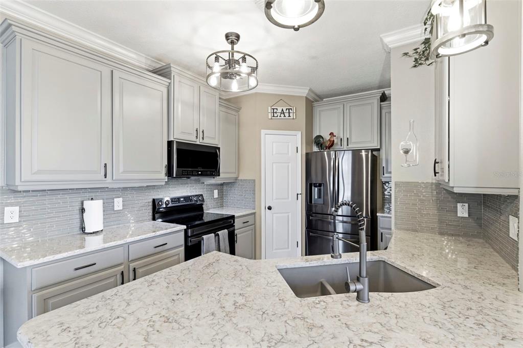8408 Shallow Creek Court New Port Richey, FL 34653 - Photo 13 of 47 a kitchen with stainless steel appliances kitchen island granite countertop a sink dishwasher and a stove with wooden floor
