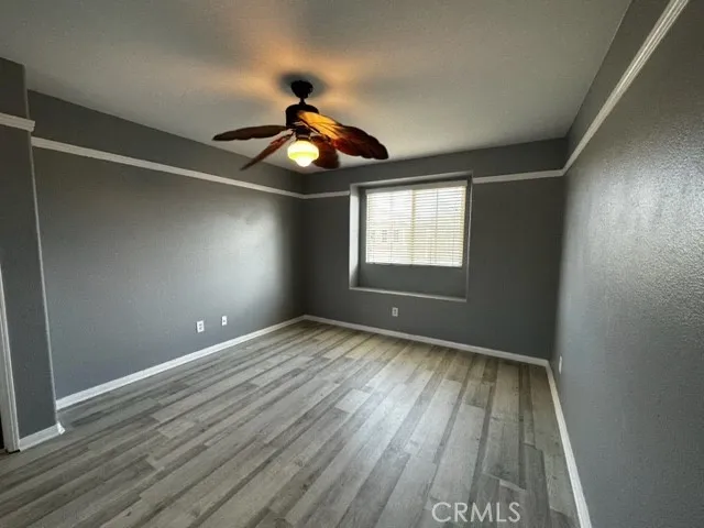 an empty room with wooden floor chandelier fan and windows