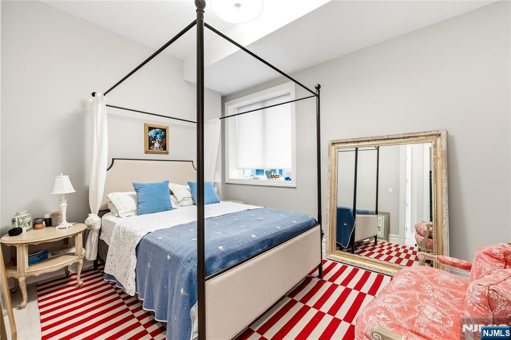 1228 River Road Edgewater, NJ 07020 - Photo 27 of 49 a bedroom with a bed and a chandelier