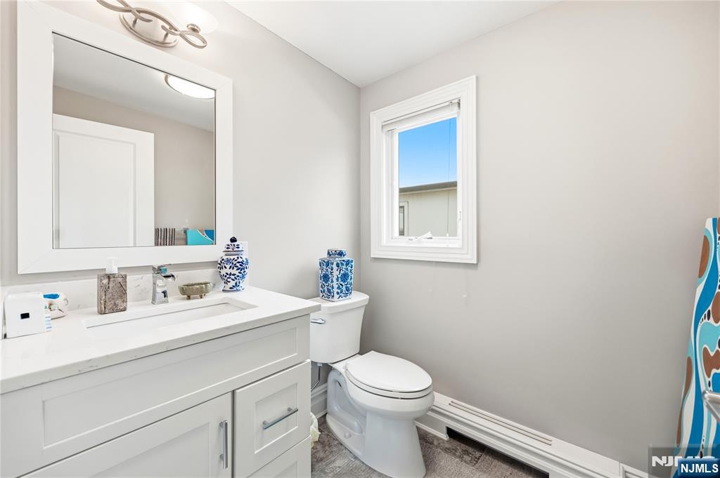 1228 River Road Edgewater, NJ 07020 - Photo 34 of 49 a bathroom with a toilet a sink a vanity and mirror