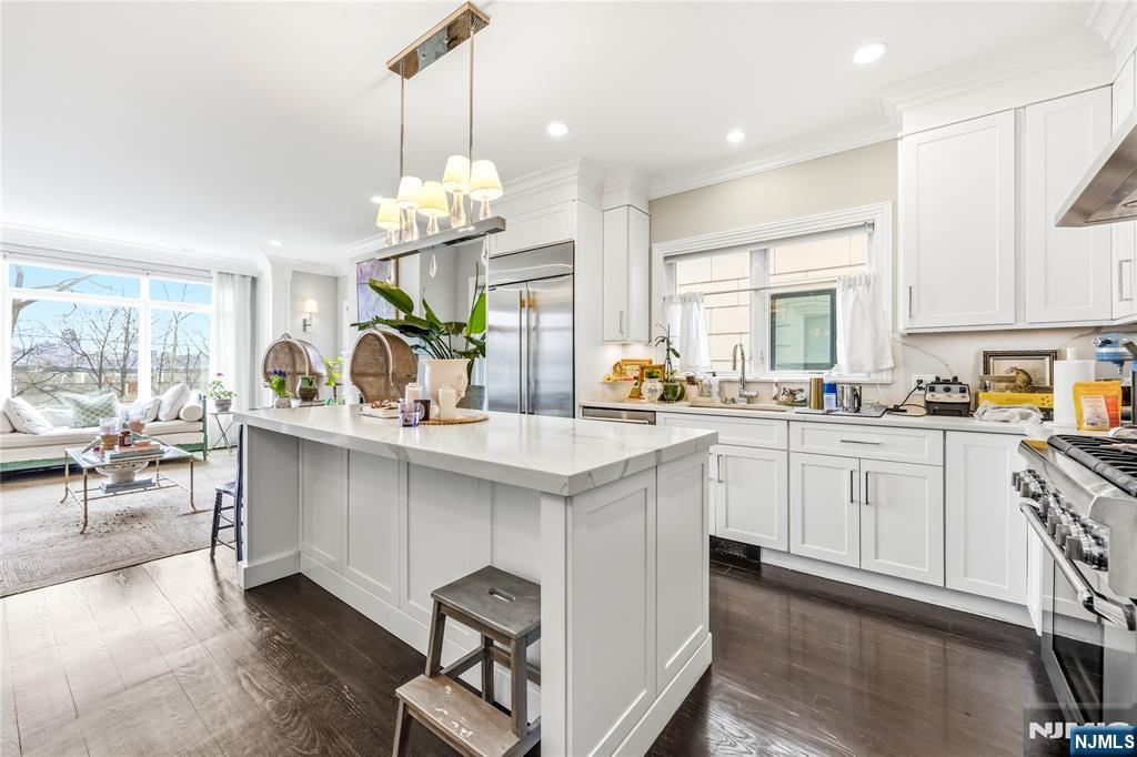 1228 River Road Edgewater, NJ 07020 - Photo 7 of 49 a kitchen with white cabinets and chandelier