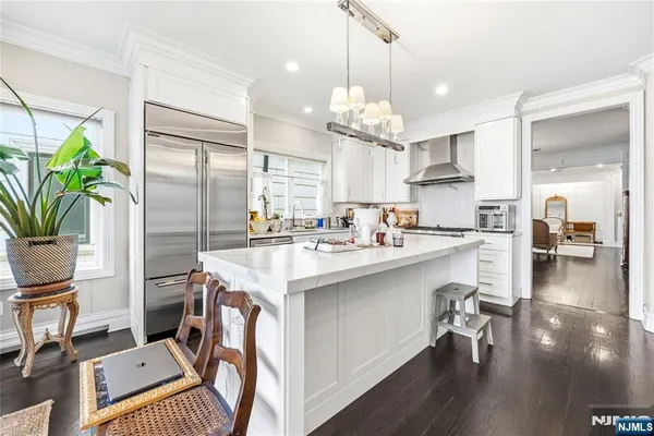 a open kitchen with stainless steel appliances granite countertop a refrigerator a stove a sink dishwasher a dining table and chairs with wooden floor