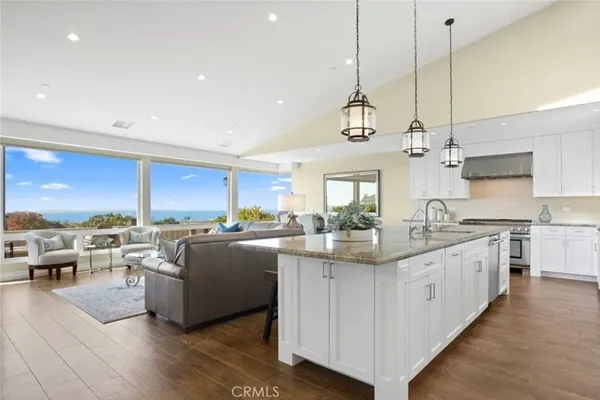 a kitchen with stainless steel appliances granite countertop a sink a stove and a wooden floors