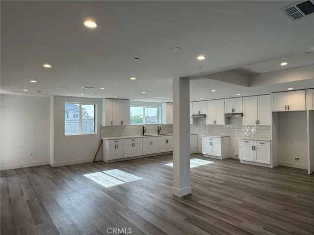 a large kitchen with stainless steel appliances refrigerator a stove top oven and a wooden floors