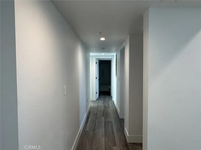 a view of a hallway with wooden floor and a bathroom