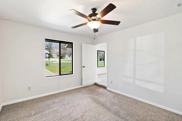 an empty room with windows and ceiling fan