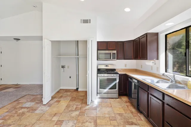 a large kitchen with stainless steel appliances granite countertop a stove a sink and a refrigerator