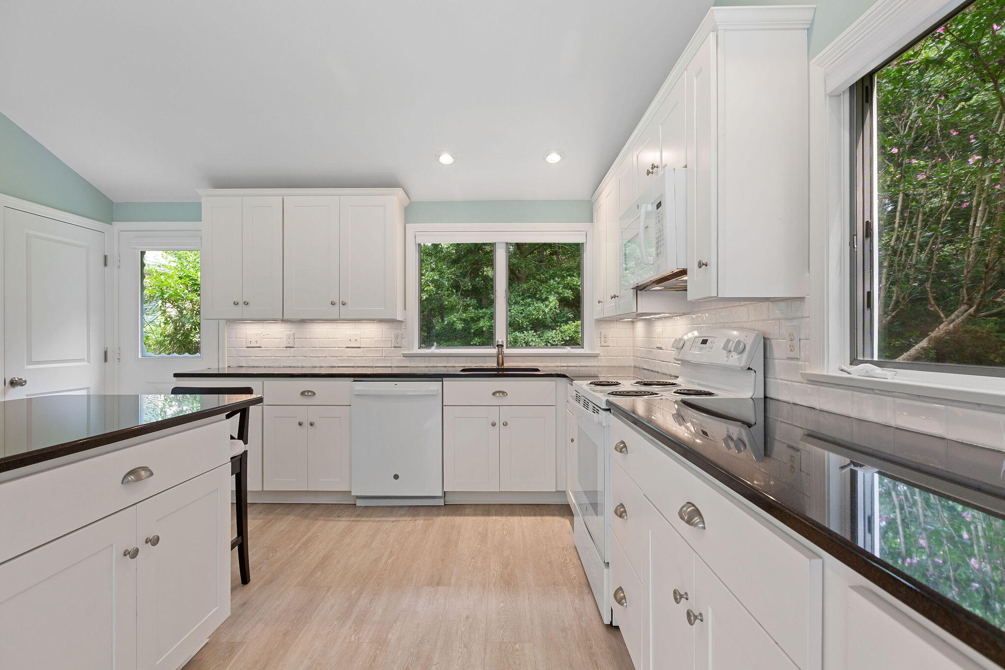 75 Monument Road Orleans, MA 02653 - Photo 32 of 61 a kitchen with granite countertop white cabinets white appliances a large window and a sink