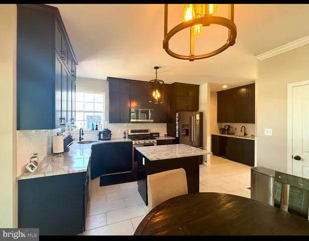 a kitchen with stainless steel appliances kitchen island granite countertop a sink dishwasher a refrigerator with white cabinets and wooden floor