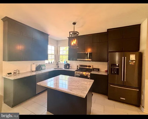 a kitchen with a sink a kitchen island stainless steel appliances cabinets and a counter top space