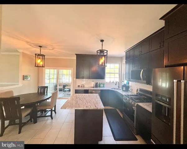 a large kitchen with kitchen island a sink stainless steel appliances and furniture