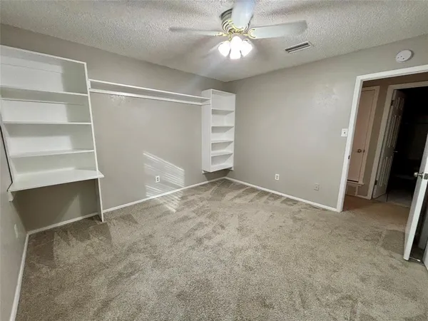 an empty room with closet and a ceiling fan