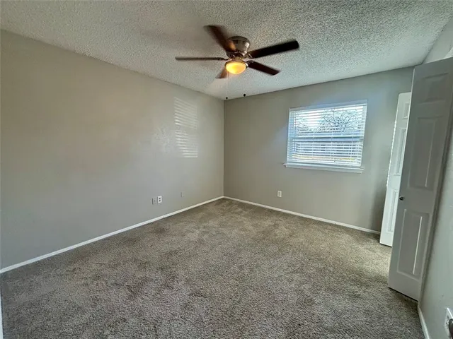an empty room with ceiling fan and window
