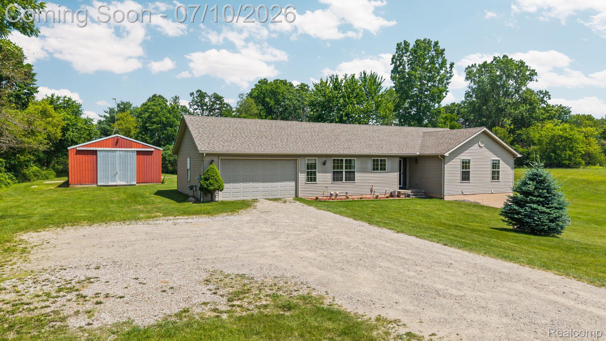 3144 North Nicholson Road Fowlerville, MI 48836 - Photo 11 of 70 Ranch-style residence featuring a gravel driveway, attached two-car garage, and a separate red outbuilding with dual barn doors