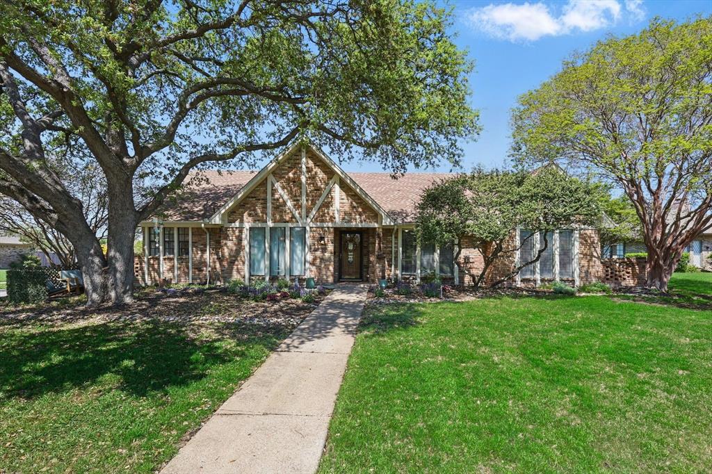 View of front of home with a front yard, brick siding, and a shingled roof