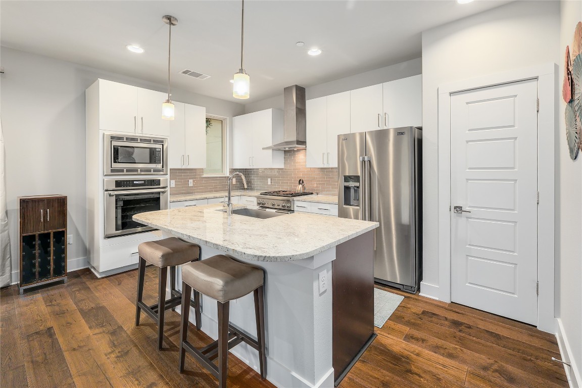 1205 Elm Street, Unit 8 Austin, TX 78703 - Photo 9 of 26 Kitchen with stainless steel appliance, white cabinetry, pendant lighting, and a kitchen island.