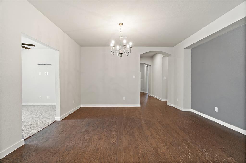 1401 Macaw Court Little Elm, TX 75068 - Photo 6 of 25 Unfurnished dining area featuring arched walkways, a chandelier, dark wood-style floors, and ceiling fan