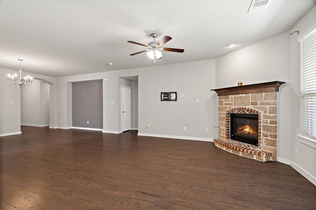 1401 Macaw Court Little Elm, TX 75068 - Photo 8 of 25 Unfurnished living room with dark wood-type flooring, a fireplace, a chandelier, ceiling fan, and arched walkways