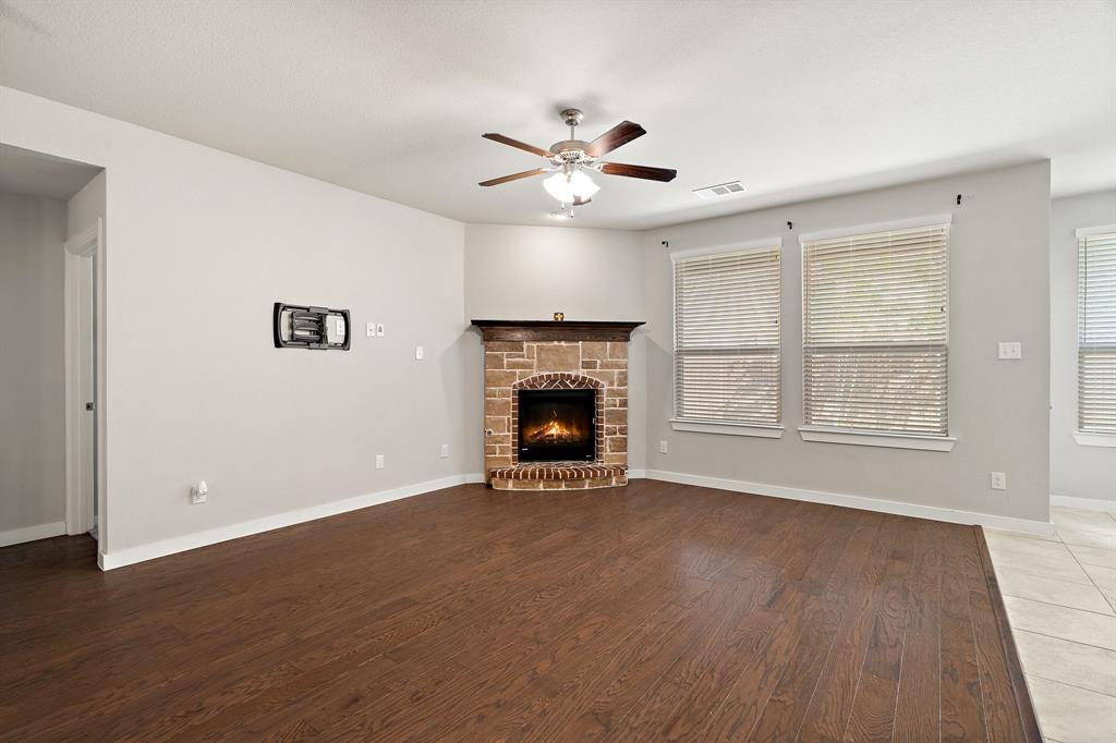 1401 Macaw Court Little Elm, TX 75068 - Photo 9 of 25 Unfurnished living room with a stone fireplace, wood finished floors, and ceiling fan