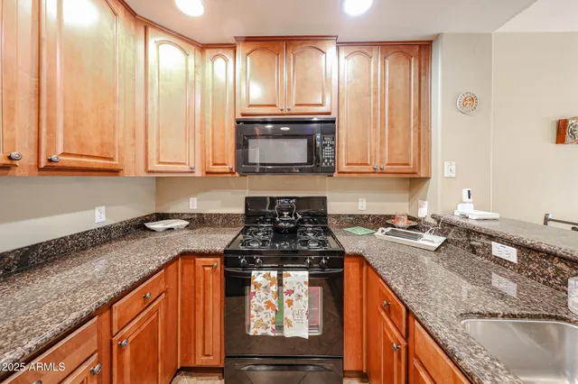 a kitchen with granite countertop a stove sink and cabinets