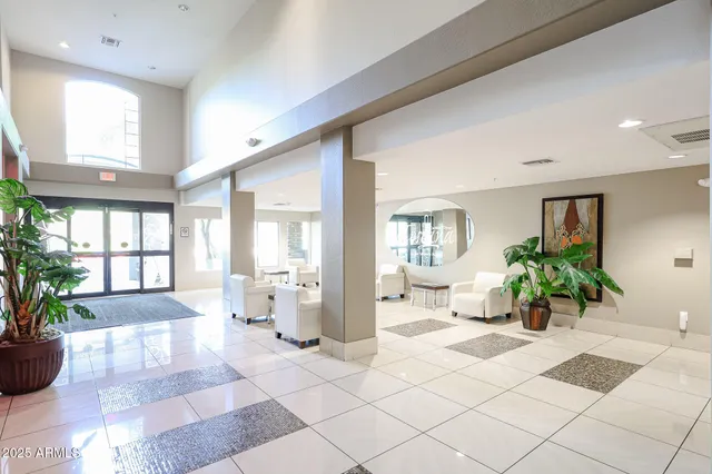 a living room with furniture a rug kitchen view and a large window