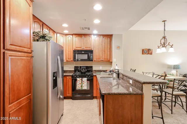 a kitchen with stainless steel appliances granite countertop a refrigerator a stove a sink and a microwave