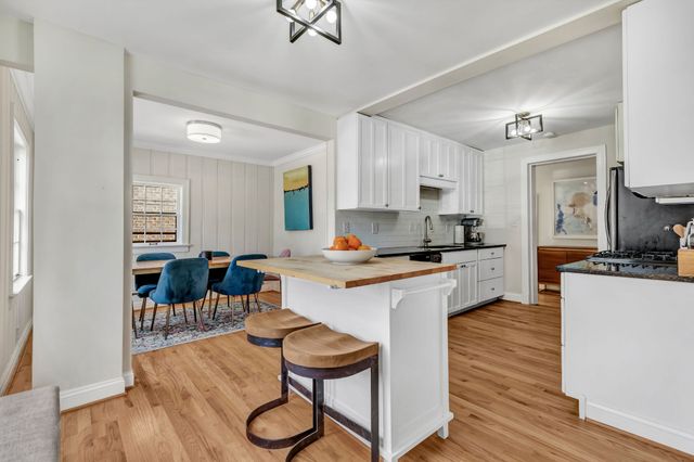 a kitchen with stainless steel appliances granite countertop a sink dishwasher a refrigerator a stove top oven a dining table and chairs with wooden floor