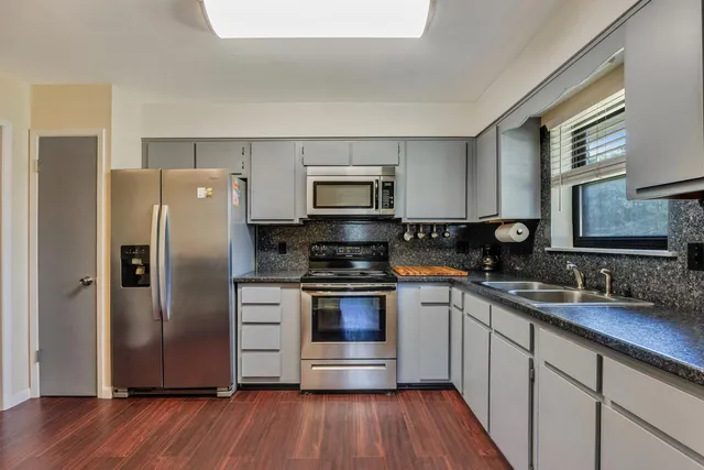 a kitchen with granite countertop a refrigerator and a stove top oven